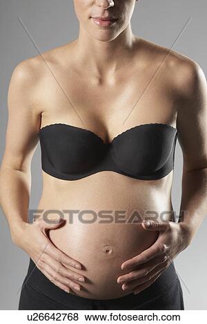 Pregnant woman touching abdomen mid section studio shot View Large Photo Image Stock Photo - Pregnant woman touching abdomen mid section studio shot. Fotosearch