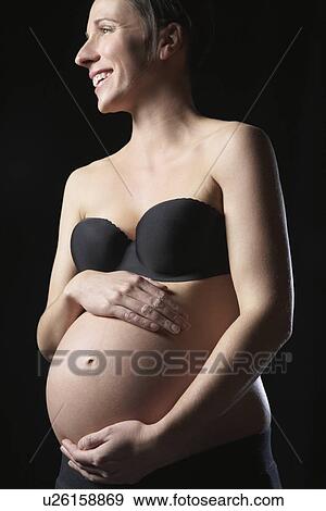 Pregnant woman touching abdomen smiling studio shot View Large Photo Image Stock Photo - Pregnant woman touching abdomen smiling studio shot. Fotosearch
