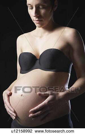 Pregnant woman touching abdomen studio shot View Large Photo Image Stock Image - Pregnant woman touching abdomen studio shot. Fotosearch