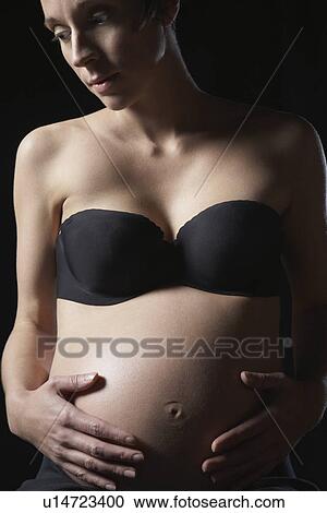 Pregnant woman touching abdomen studio shot View Large Photo Image Stock Image - Pregnant woman touching abdomen studio shot. Fotosearch