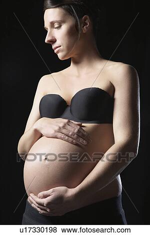 Pregnant woman touching abdomen studio shot View Large Photo Image Stock Photo - Pregnant woman touching abdomen studio shot. Fotosearch