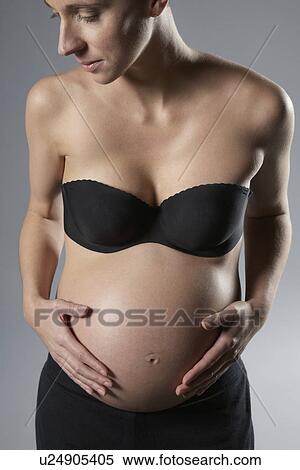 Pregnant woman touching abdomen studio shot View Large Photo Image Stock Photography - Pregnant woman touching abdomen studio shot. Fotosearch