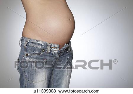 Pregnant woman wearing jeans mid section studio shot View Large Photo Image Stock Photo - Pregnant woman wearing jeans mid section studio shot. Fotosearch