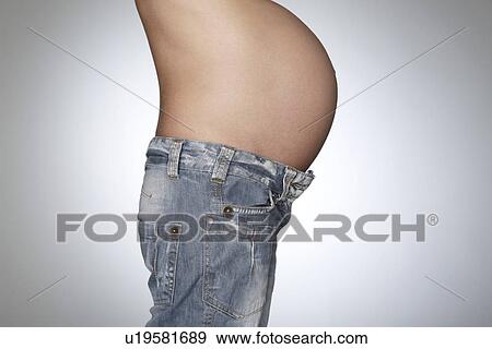 Pregnant woman wearing jeans mid section side view studio shot View Large Photo Image Stock Photo - Pregnant woman wearing jeans mid section side view studio shot. Fotosearch