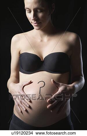 Picture - Pregnant woman with question mark on abdomen studio shot. Fotosearch