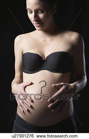 Stock Photograph - Pregnant woman with question mark on abdomen studio shot. Fotosearch