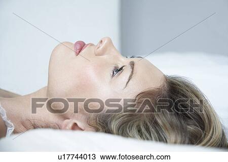 Stock Image - Profile of young woman in underwear lying on bed close-up. Fotosearch