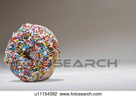 Stock Image - Rainbow sprinkles on doughnut. Fotosearch
