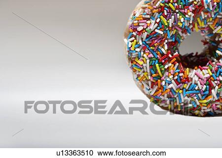 Stock Image - Rainbow sprinkles on doughnut. Fotosearch
