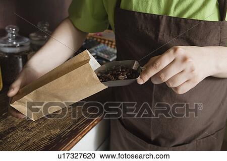 Stock Image - Salesperson Scooping Coffee Beans Into Bag. Fotosearch
