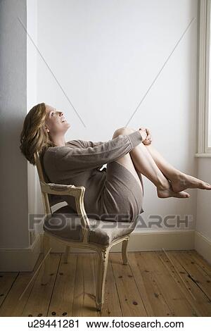 Stock Image - Semi dress woman relaxing on old fashioned chair. Fotosearch