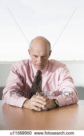 Stock Image - Serious Businessman Sitting at Meeting Table. Fotosearch