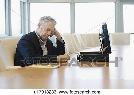 Stock Image - Serious Businessman with Open Briefcase Head on Hand. Fotosearch