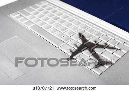 Stock Image - Shadow of jumbo jet over apple macintosh keyboard. Fotosearch