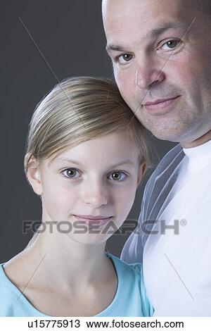 Stock Image - Studio portrait of father and daughter smiling. Fotosearch