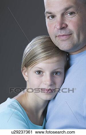 Stock Image - Studio portrait of father and daughter smiling. Fotosearch