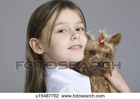 Stock Image - Studio portrait of girl holding dog. Fotosearch