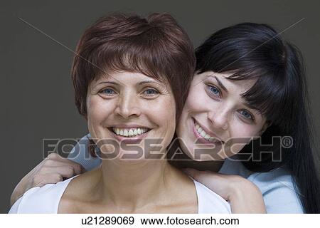 Studio portrait of young woman embracing mother View Large Photo Image Stock Photo - Studio portrait of young woman embracing mother. Fotosearch