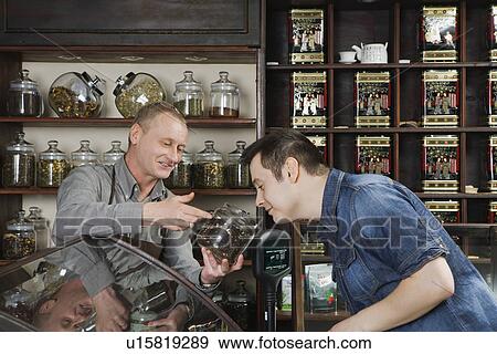 Stock Photo - Tea Shop Owner Showing Tea to Customer. Fotosearch