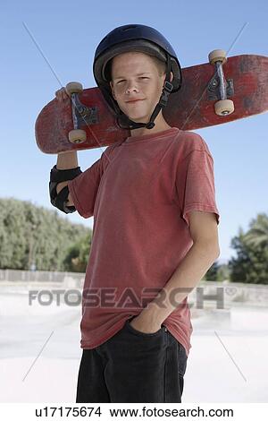 Teenage boy (13-15) holding skateboard at skateboard park portrait View Large Photo Image Picture - Teenage boy (13-15) holding skateboard at skateboard park portrait. Fotosearch