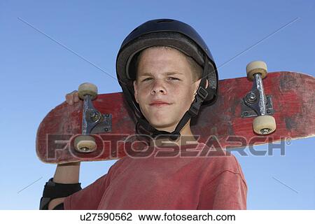 Teenage boy (13-15) holding skateboard outdoors portrait View Large Photo Image Stock Image - Teenage boy (13-15) holding skateboard outdoors portrait. Fotosearch