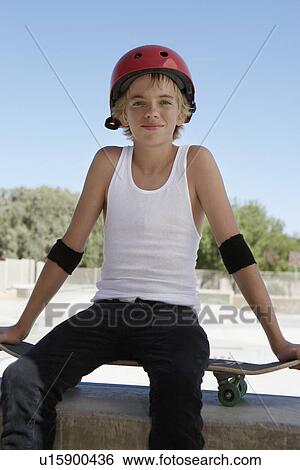 Stock Photograph - Teenage boy (13-15) with skateboard at skateboard park portrait. Fotosearch