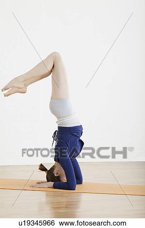 Stock Photograph - Teenage girl (16-17) balancing on head. Fotosearch