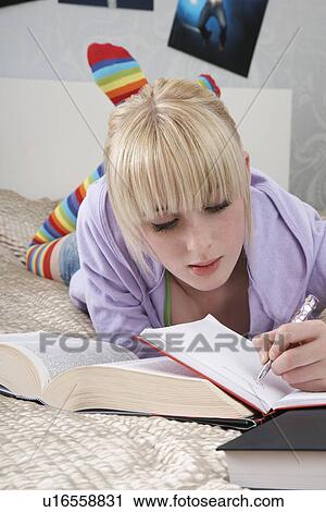 Teenage girl (16-17) doing homework on bed View Large Photo Image Stock Image - Teenage girl (16-17) doing homework on bed. Fotosearch