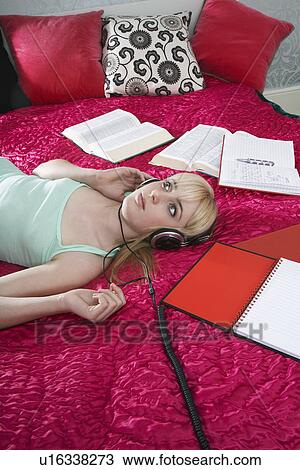 Teenage girl (16-17) listening music on bed surrounded by books View Large Photo Image Stock Image - Teenage girl (16-17) listening music on bed surrounded by books. Fotosearch