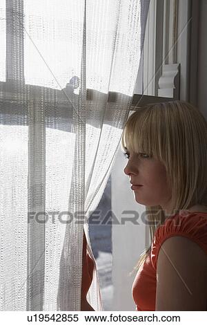 Teenage girl (16-17) looking through window View Large Photo Image Stock Photography - Teenage girl (16-17) looking through window. Fotosearch