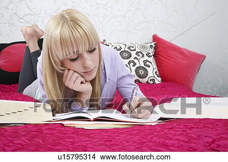 Teenage girl (16-17) lying on bed writing View Large Photo Image Picture - Teenage girl (16-17) lying on bed writing. Fotosearch