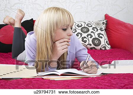 Teenage girl (16-17) lying on bed writing View Large Photo Image Stock Image - Teenage girl (16-17) lying on bed writing. Fotosearch