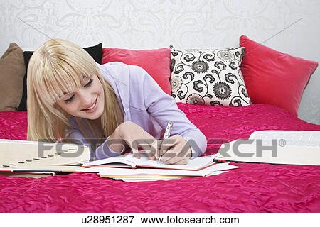 Teenage girl (16-17) lying on bed writing View Large Photo Image Stock Photo - Teenage girl (16-17) lying on bed writing. Fotosearch