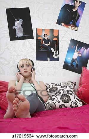 Teenage girl (16-17) sitting on bed listening to music View Large Photo Image Picture - Teenage girl (16-17) sitting on bed listening to music. Fotosearch