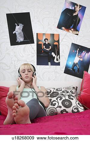 Teenage girl (16-17) sitting on bed listening to music eyes closed View Large Photo Image Stock Photo - Teenage girl (16-17) sitting on bed listening to music eyes closed. Fotosearch