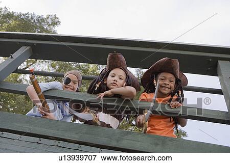 Stock Photo - Three boys (7-9) wearing costumes looking down from bridge. Fotosearch