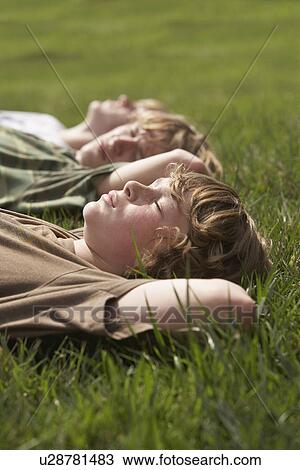 Three teenage brothers (13-17) lying down on front lawn close up View Large Photo Image Stock Image - Three teenage brothers (13-17) lying down on front lawn close up. Fotosearch