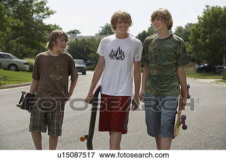 Three teenage brothers (13-17) walking on street carrying skateboards View Large Photo Image Stock Photo - Three teenage brothers (13-17) walking on street carrying skateboards. Fotosearch