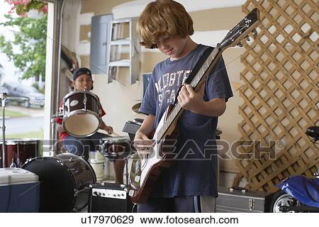 Two boys (10-12) playing drums and guitar in garage View Large Photo Image Stock Photo - Two boys (10-12) playing drums and guitar in garage. Fotosearch