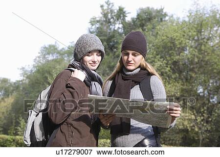 Two girlfriends reading map outdoors View Large Photo Image Stock Photo - Two girlfriends reading map outdoors. Fotosearch