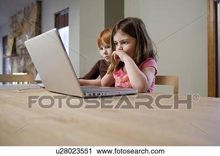 Two girls (5-6) at table using laptop View Large Photo Image Stock Image - Two girls (5-6) at table using laptop. Fotosearch