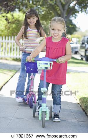 Stock Photo - Two girls on scooters. Fotosearch