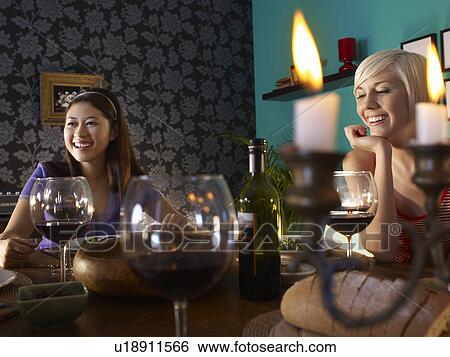 Two women sitting at dining table View Large Photo Image Stock Photograph - Two women sitting at dining table. Fotosearch