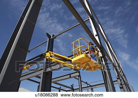 Welder working from cherry picker on warehouse construction View Large Photo Image Stock Photo - Welder working from cherry picker on warehouse construction. Fotosearch