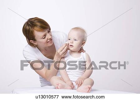 Stock Photo - Woman cleaning baby's (1-2) face studio shot. Fotosearch