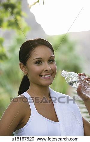 Stock Image - Woman drinking water in park. Fotosearch