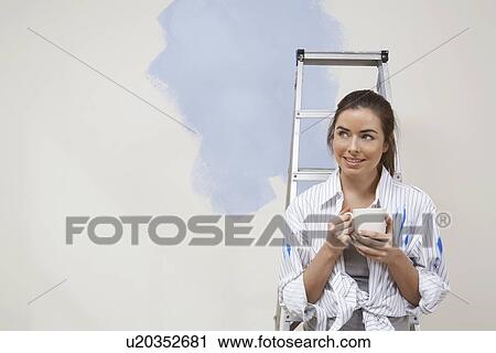 Woman having coffee by half-painted wall View Large Photo Image Stock Image - Woman having coffee by half-painted wall. Fotosearch