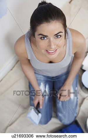 Stock Photograph - Woman kneeling with paintbrush portrait. Fotosearch