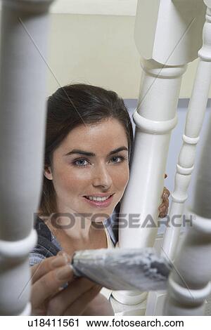 Stock Image - Woman painting behind banister. Fotosearch