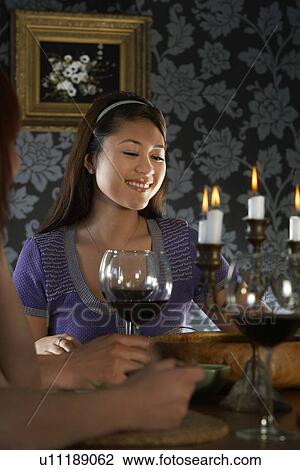 Stock Image - Woman sitting with friends at dining table. Fotosearch